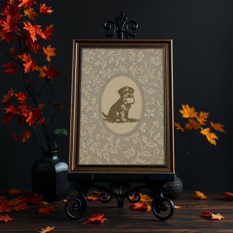 Puede incluir: Un marco dorado presenta una imagen de un perro sosteniendo un rollo de papel higi&eacute;nico, sobre un fondo floral. El marco se exhibe en un caballete de metal negro adornado con volutas decorativas. Hojas de oto&ntilde;o y un jarr&oacute;n negro en el fondo.