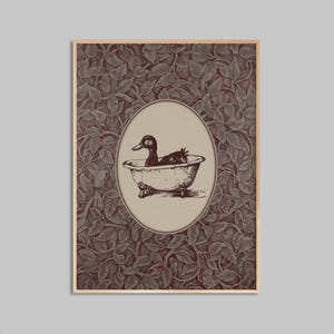 Peut inclure: Une affiche encadrée avec une illustration vintage d'un canard dans une baignoire. Le canard est en noir et blanc, dans un cadre ovale. Le fond présente un motif de feuilles répétitif dans des tons bruns et rouges.
