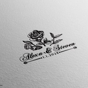 May include: Black and white wedding invitation design with a rose and leaves. The text reads "Alexa & Steven 1.1.2028".