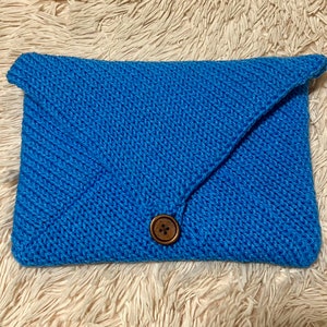 May include: A blue crocheted clutch with a brown button closure.