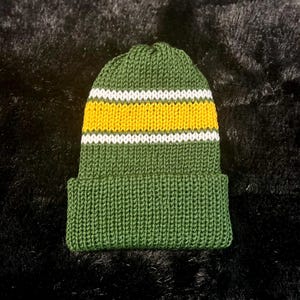 May include: Green knit beanie with white and yellow stripes.