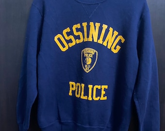 May include: Navy blue sweatshirt with the word "OSSINING" arched across the chest in yellow lettering. Below, a shield graphic with "OSSINING POLICE" and "1813 N.Y." is centered. The word "POLICE" is printed below the shield in yellow.