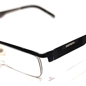 Puede incluir: Gafas Carrera negras con montura rectangular y lentes transparentes. Las gafas tienen un diseño elegante y moderno con el logotipo de Carrera en la patilla. Las monturas tienen un acabado negro mate.