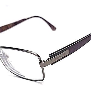 May include: Rectangular eyeglasses with a dark metallic frame and dark purple temples. The temples feature a small rectangular metal plate with the text Michael Kors engraved on the side. The clear lenses are set within a thin metal rim.