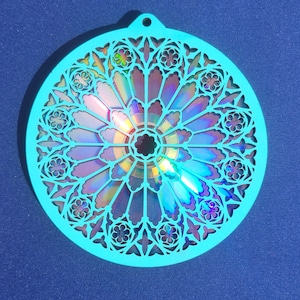 May include: A teal blue circular ornament with a cut-out design resembling a stained glass window. A rainbow iridescent CD is visible through the cut-outs.
