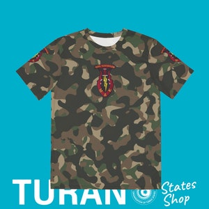 May include: Camouflage t-shirt with a red, yellow, and black emblem featuring a dagger, lightning bolt, and the text "OZEL KUVVETLER" and "MAK".