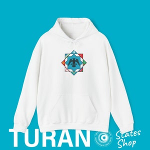 Op de afbeelding: Witte hoodie met een blauw en wit sterontwerp met een zwarte adelaar en de vlaggen van verschillende landen. De tekst "TURAN" is gedrukt in de linkerbenedenhoek van de afbeelding. De tekst "States Shop" is gedrukt in de rechterbenedenhoek van de afbeelding.