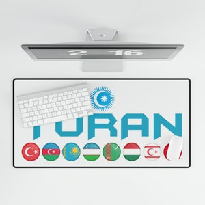 May include: A white desk mat with the word "TURAN" in blue letters. The mat features a circle with a star and crescent moon in the center, and a row of eight circular flags representing different countries. A white keyboard and mouse are on the mat.