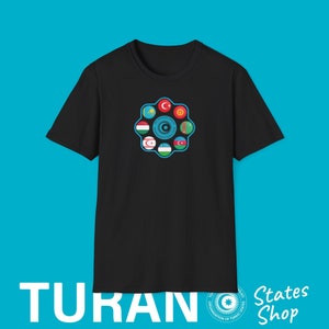 Op de afbeelding: Zwart t-shirt met een cirkelvormig ontwerp met vlaggen van verschillende landen. Het ontwerp is omgeven door een lichtblauwe rand. Het woord "TURAN" staat in het wit linksonder, met "States Shop" rechts.