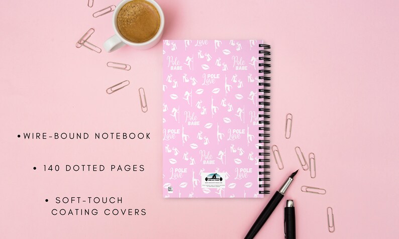 K&ouml;nnte beinhalten: Ein pinkfarbenes, drahtgebundenes Notizbuch mit schwarzer Spiralbindung, verziert mit wei&szlig;en Silhouetten, den Worten "Pole Babe" und "Pole Love". Es hat 140 gepunktete Seiten und Soft-Touch-Beschichtungen. Eine Tasse Kaffee, ein Stift und B&uuml;roklammern sind ebenfalls sichtbar.