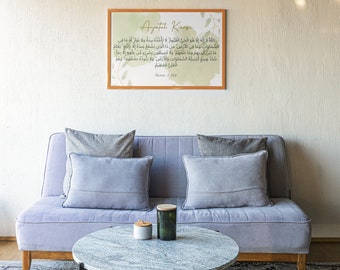 Op de afbeelding: Een digitale print van een islamitische quote in Arabisch schrift, ingelijst in een licht houten lijst. De print hangt aan een muur boven een lichtgrijze bank met grijze kussens. Een ronde marmeren salontafel staat voor de bank.