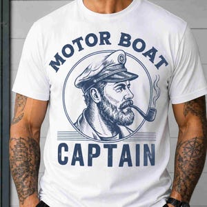 May include: White t-shirt featuring a blue illustration of a motor boat captain smoking a pipe. The text "MOTOR BOAT CAPTAIN" is printed above and below the illustration in blue, creating a nautical theme.