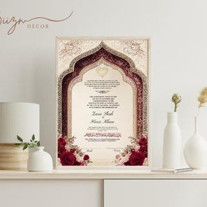 May include: Framed wedding certificate with a decorative arch design in burgundy and cream. The certificate includes the names Zara Shah and Haris Khan, with floral accents. The frame is light-colored, and the overall aesthetic is elegant.