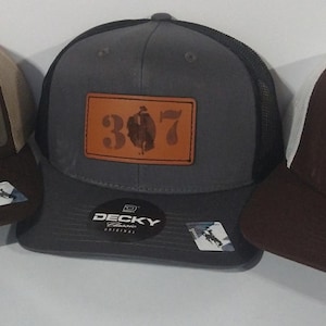 May include: Three trucker hats with a brown, gray, and white mesh back. Each hat has a brown leather patch with the number 307 on it.