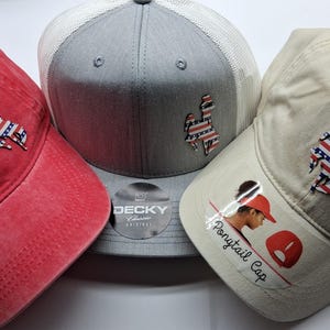 May include: Three baseball caps in red, gray, and beige. Each cap features a patch with a design in the colors of the American flag. The beige cap has the text "Ponytail Cap" and an image of a person.