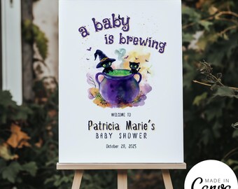 May include: A baby shower sign on an easel. The sign features the text "a baby is brewing" above a watercolor illustration of a cauldron with two black cats. The sign reads "Welcome to Patricia Marie's Baby Shower October 28, 2025."