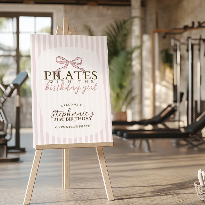 Peut inclure: Panneau de bienvenue sur chevalet en bois, avec un design &agrave; rayures roses et blanches. Le panneau indique "Pilates avec la fille d'anniversaire" et souhaite la bienvenue aux invit&eacute;s &agrave; l'anniversaire de Stephanie, 21 ans, chez Glow & Flow Pilates.