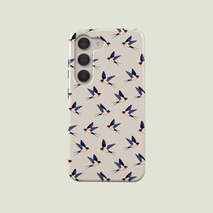 May include: A mobile phone case featuring a pattern of swallows. The birds are in flight, with blue, black, and red details, set against a light beige backdrop. The case has a triple-lens camera module.