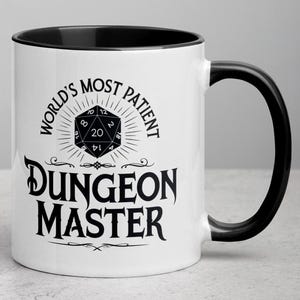 Puede incluir: Taza de cerámica blanca con borde y asa negros. La taza presenta un gráfico en blanco y negro de un dado de veinte caras con el texto "World's Most Patient Dungeon Master".