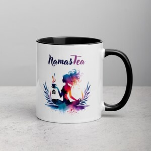 K&ouml;nnte beinhalten: Wei&szlig;e Keramiktasse mit schwarzem Rand und Henkel. Die Tasse zeigt eine farbenfrohe Illustration einer Frau in einer Yoga-Pose, die eine Tasse Tee h&auml;lt. Der Text "Namastea" ist in Schwarz auf die Tasse gedruckt.