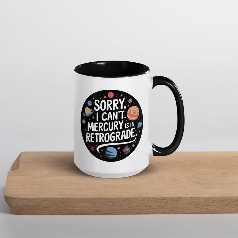 Peut inclure: Une tasse en c&eacute;ramique blanche avec un bord et une poign&eacute;e noirs. La tasse pr&eacute;sente un motif noir et blanc de plan&egrave;tes et d'&eacute;toiles avec le texte "D&eacute;sol&eacute;, je ne peux pas. Mercure est r&eacute;trograde."