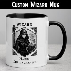 Peut inclure: Mug en céramique blanche avec intérieur et anse noirs. La tasse présente une illustration en noir et blanc d'un magicien avec le texte "WIZARD" et "Hanna The Enchanted". Le haut de la tasse porte le texte "CUSTOM WIZARD MUG".