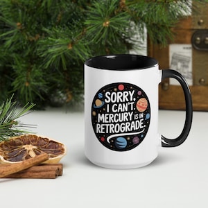 Peut inclure: Une tasse en c&eacute;ramique blanche avec un bord et une poign&eacute;e noirs. La tasse pr&eacute;sente un cercle noir avec des plan&egrave;tes color&eacute;es et le texte "D&eacute;sol&eacute;, je ne peux pas. Mercure est r&eacute;trograde."