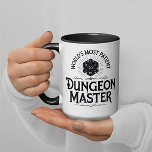 May include: White ceramic mug with a black rim and handle. The mug features a black and white graphic of a twenty-sided die with the text "World's Most Patient Dungeon Master".