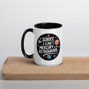 Peut inclure: Une tasse en c&eacute;ramique blanche avec un bord et une poign&eacute;e noirs. La tasse pr&eacute;sente un motif noir et blanc de plan&egrave;tes et le texte "D&eacute;sol&eacute;, je ne peux pas. Mercure est r&eacute;trograde."