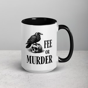 May include: White ceramic mug with a black interior and handle. The mug features a black and white illustration of a raven perched on a skull. The text "FEE OR MURDER" is printed below the raven and skull.
