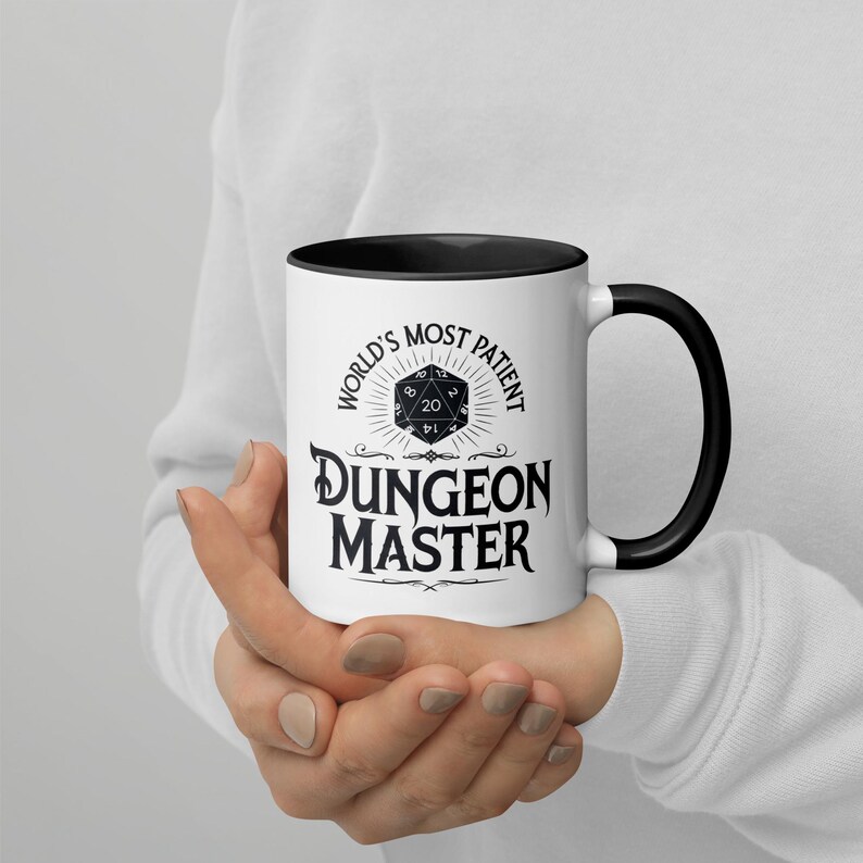 May include: White ceramic mug with a black rim and handle. The mug has a black graphic that says "World's Most Patient Dungeon Master" with a black and white 20-sided die graphic.