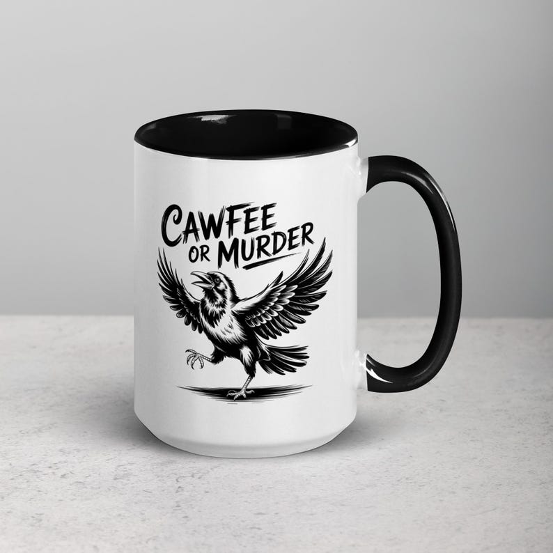 May include: White ceramic coffee mug with a black interior and handle. The mug features a black and white illustration of a crow with outstretched wings and the text "CAWFEE OR MURDER" in a stylized font.