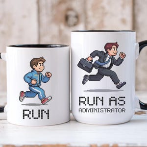 Könnte beinhalten: Zwei weiße Keramikbecher mit schwarzen Rändern. Der Becher links zeigt ein Pixelbild einer laufenden Person und den Text "RUN". Der Becher rechts zeigt ein Pixelbild einer laufenden Person mit einem Aktenkoffer und den Text "RUN AS ADMINISTRATOR".