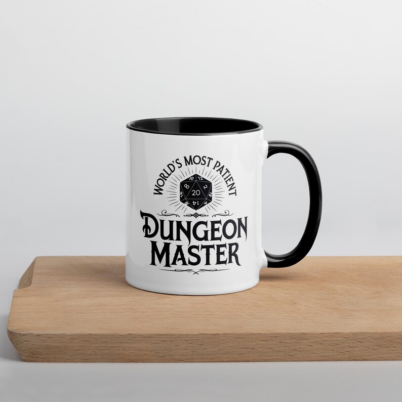 May include: White ceramic mug with a black rim and handle. The mug features a black and white graphic of a twenty-sided die with the text "World's Most Patient Dungeon Master".