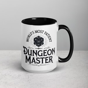 May include: White ceramic mug with a black rim and handle. The mug features a black and white graphic of a twenty-sided die with the text "World's Most Patient Dungeon Master".
