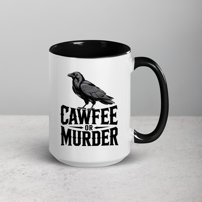 May include: White ceramic coffee mug with a black interior and handle. The mug features a black and gray illustration of a raven perched above the words "CAWFEE OR MURDER" in a bold, stylized font. A humorous gift.