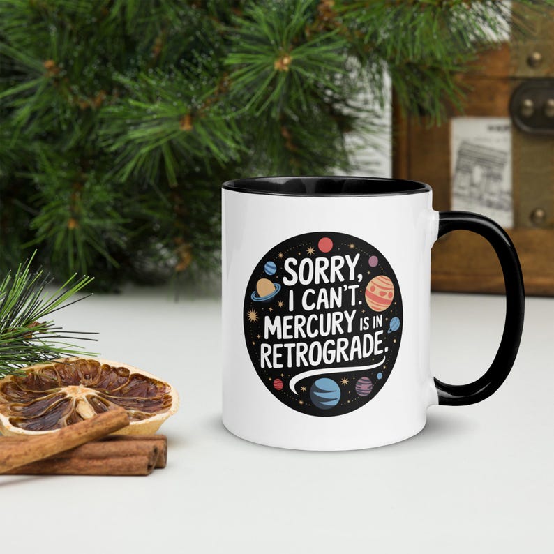 Peut inclure: Une tasse en c&eacute;ramique blanche avec un bord et une poign&eacute;e noirs. La tasse pr&eacute;sente un motif noir et blanc de plan&egrave;tes et d'&eacute;toiles avec le texte "D&eacute;sol&eacute;, je ne peux pas. Mercure est r&eacute;trograde."