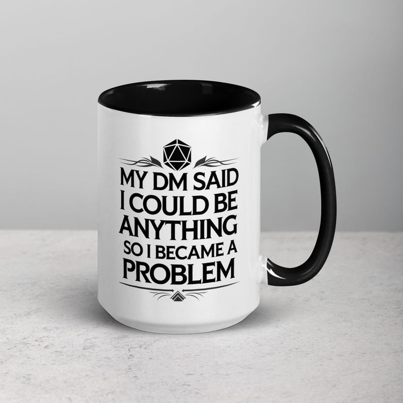 May include: White ceramic mug with a black interior and handle. The mug features the text "MY DM SAID I COULD BE ANYTHING SO I BECAME A PROBLEM" in black, along with a geometric design. A fun gift for a Dungeons and Dragons player.