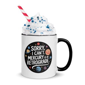 Peut inclure: Une tasse en c&eacute;ramique blanche avec une anse noire. La tasse pr&eacute;sente un cercle noir avec des plan&egrave;tes color&eacute;es et le texte "D&eacute;sol&eacute;, je ne peux pas. Mercure est en r&eacute;trograde."