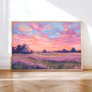 Puede incluir: Pintura de paisaje enmarcada que representa una vibrante puesta de sol sobre un campo de flores de lavanda. El cielo está lleno de tonos rosas, naranjas y azules, en un marco de madera clara.