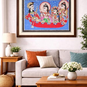 May include: A framed artwork showing figures in a boat, set against a blue background with wave patterns. The artwork is framed in a dark brown wooden frame and hangs above a grey sofa. The scene is vibrant and colourful.