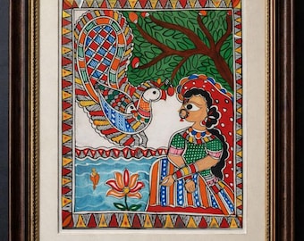 May include: Framed artwork depicting a woman and a peacock. The woman wears a green and orange dress, and the peacock is colorful. The background includes a tree, water, and a lotus flower. The frame is brown.
