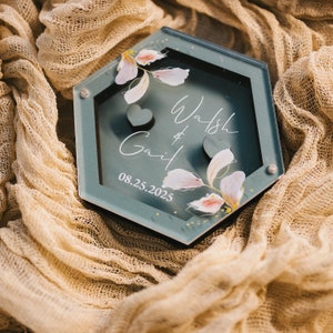 Peut inclure: Une boîte à bague hexagonale turquoise avec un motif floral et le texte "Walsh & Gail 08.25.2025".