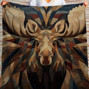Puede incluir: Una manta con un diseño geométrico de cabeza de alce. La paleta de colores incluye marrones, beiges y azules oscuros. Las astas del alce son una característica destacada. El diseño de la manta crea un efecto visual llamativo.