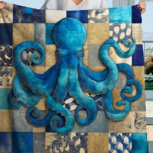 May include: A blue and gold patterned blanket featuring a large, detailed octopus design. The octopus is a vibrant shade of blue, with intricate detailing. The blanket has a patchwork design with squares of blue, gold, and patterned fabrics.
