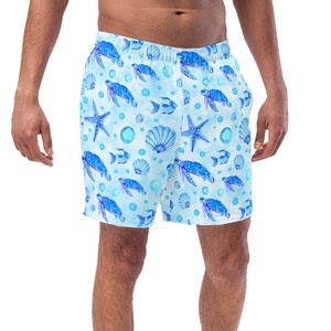 May include: Light blue swim trunks featuring an all-over print of dark blue sea turtles, starfish, seashells, and small fish. The shorts have an elastic waistband and a relaxed fit, showcasing a repeating aquatic pattern across the fabric.