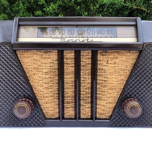 May include: A vintage brown Bakelite Motorola radio with a gold-colored dial and a woven speaker grille. The dial has numbers from 55 to 160.