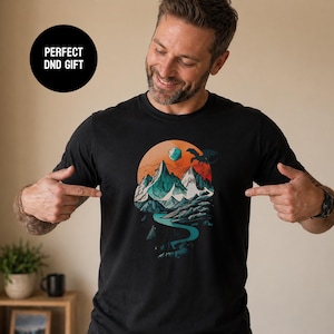 Smiling man pointing at the DnD adventure mountain shirt in black with a Perfect DnD Gift badge — vintage fantasy landscape tee shown as an ideal gift for tabletop gamers