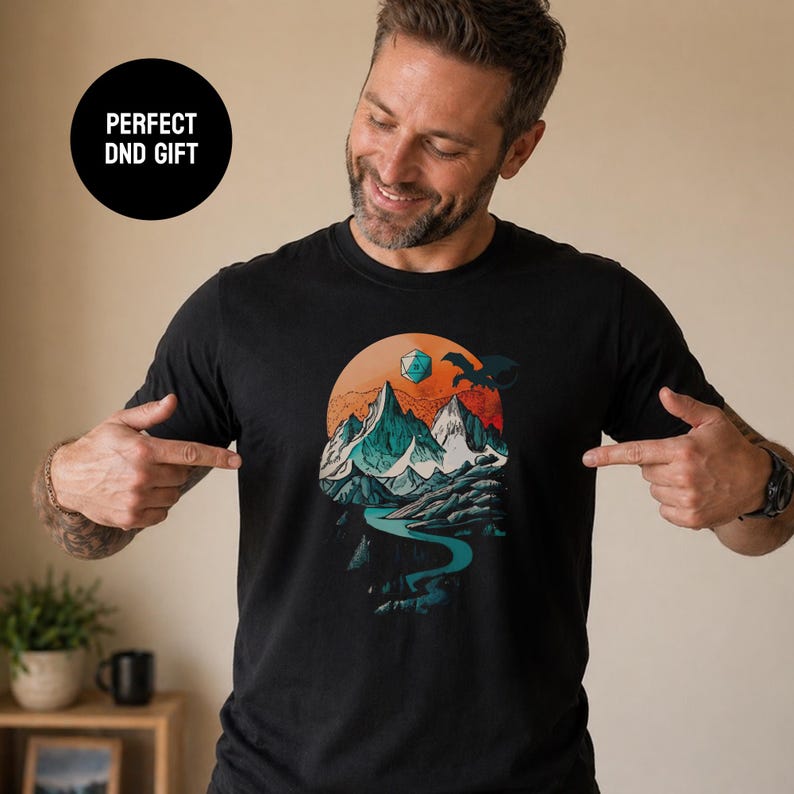 Smiling man pointing at the DnD adventure mountain shirt in black with a Perfect DnD Gift badge — vintage fantasy landscape tee shown as an ideal gift for tabletop gamers
