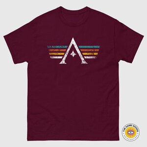 A minimalist t-shirt featuring the Arcs board game logo in a retro style. The design includes white geometric lines with a central star and vintage-colored stripes (teal, orange, red, yellow) on a dark background. Perfect for board gamers, sci-fi fans, and anyone who loves stylish and unique game night apparel.